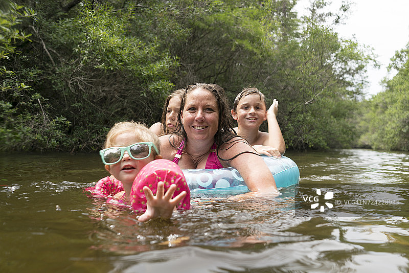 母亲和孩子们带着充气游泳圈在湖里（尼斯维尔，佛罗里达州，美国）图片素材