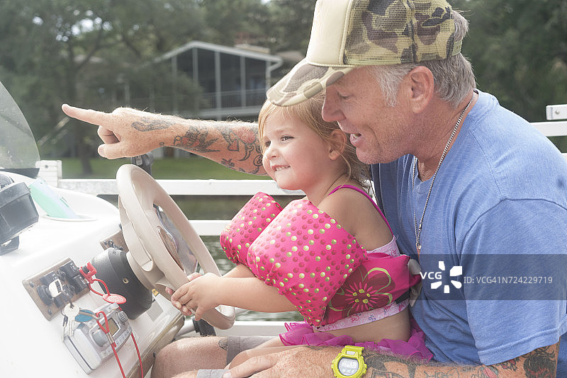 女儿帮助父亲驾驶快艇，美国佛罗里达州沙利马图片素材