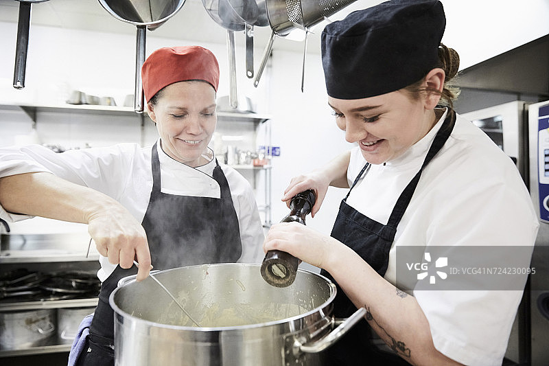 老师和女学生在商用厨房的烹饪锅中加辣椒图片素材