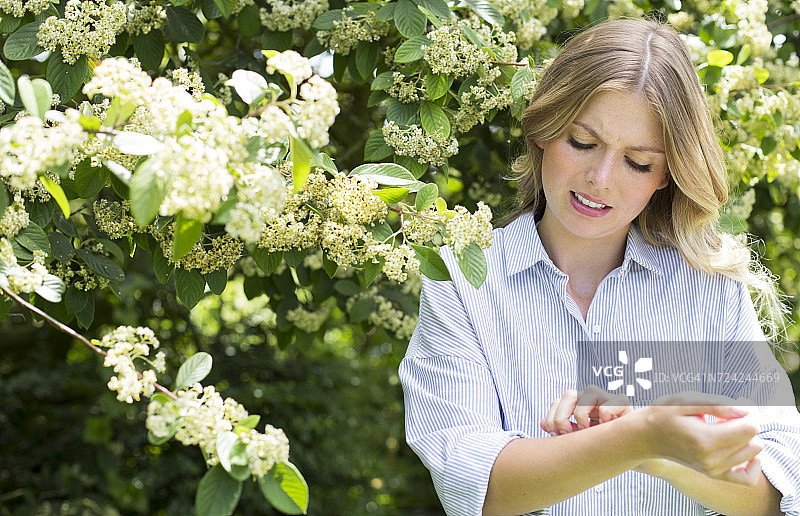在树旁挠手臂的女人图片素材