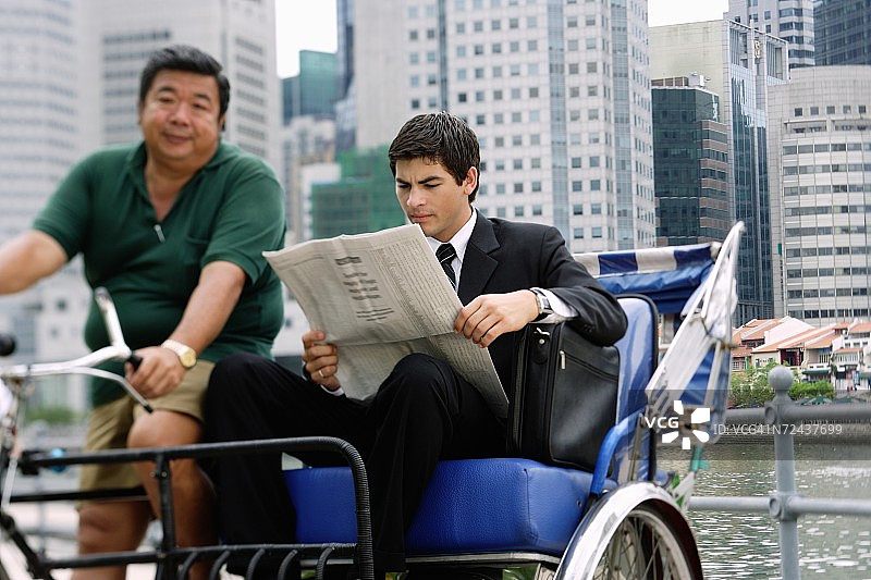 坐在三轮车上看报纸的商人图片素材