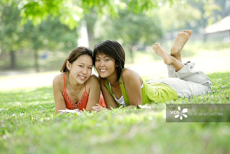 两个年轻女人躺在草地上看向镜头图片素材