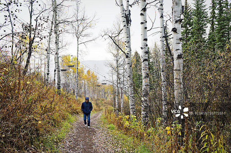 男子在秋季雨中徒步旅行图片素材