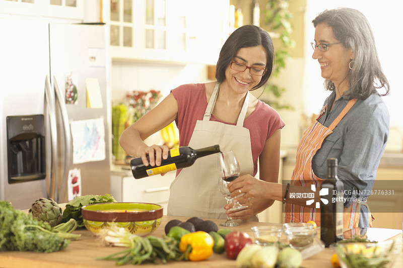 女儿在厨房给妈妈倒酒图片素材
