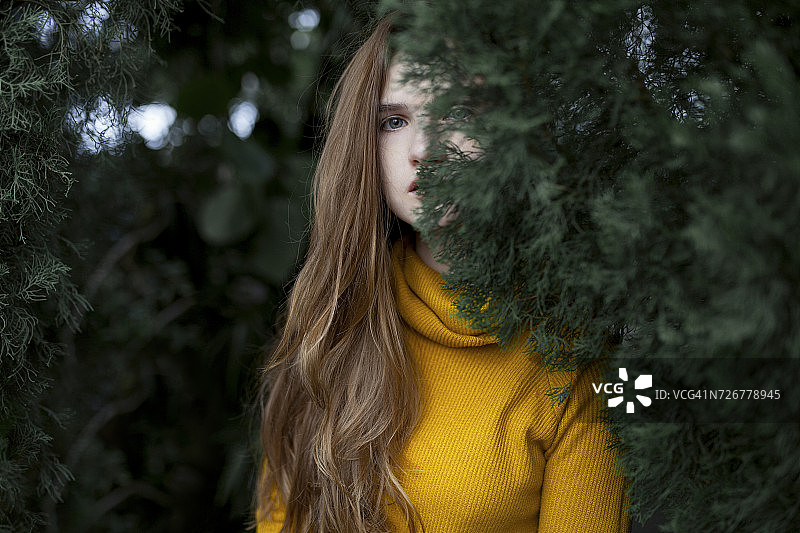 表情严肃的白人女子躲在树后图片素材