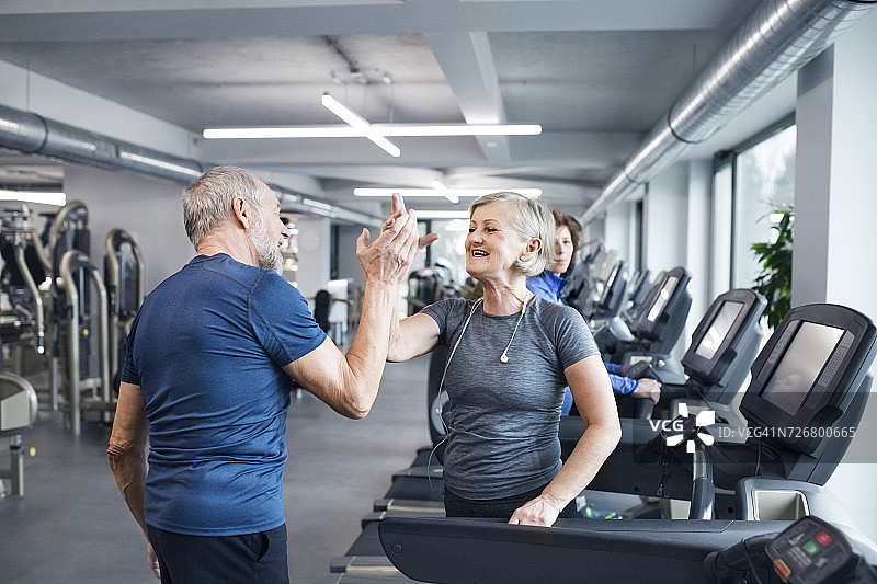 快乐的老年夫妇在健身房锻炼后击掌庆祝。图片素材