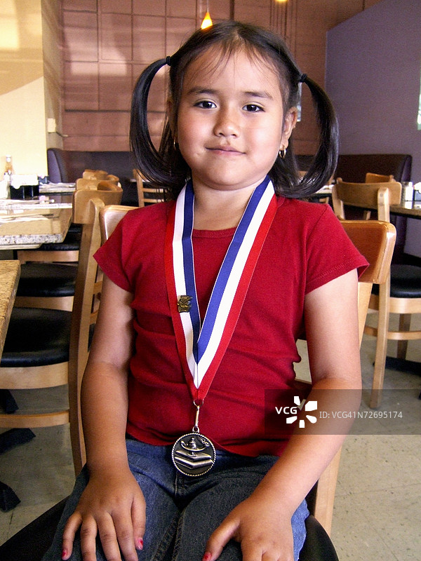 女孩在餐厅里佩戴奖牌。图片素材