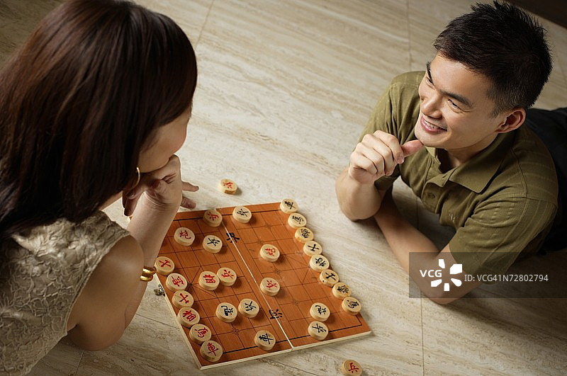 情侣躺在地板上玩中国象棋图片素材