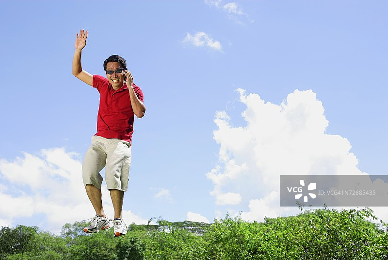 在半空中拿着手机跳跃的男人图片素材