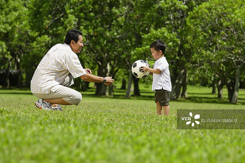父子在公园里玩足球图片素材
