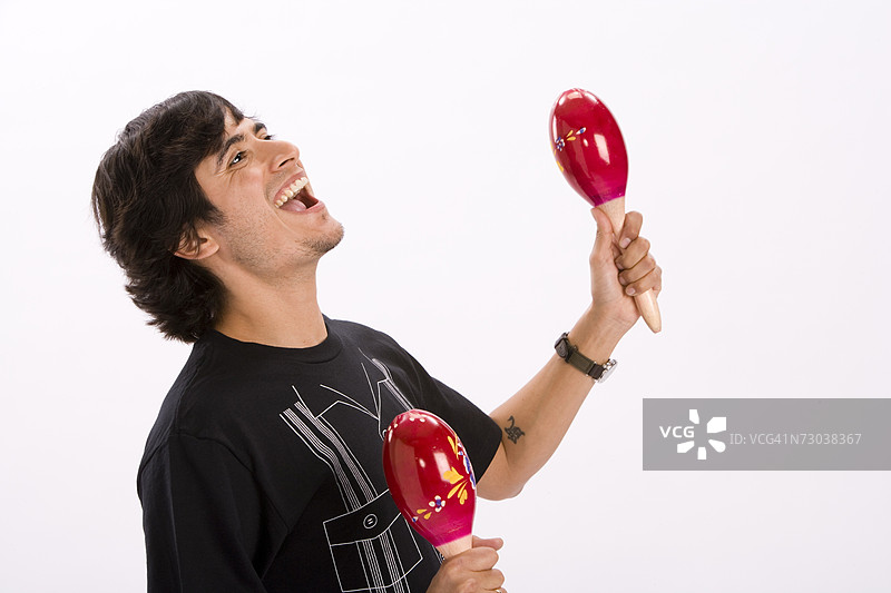 年轻男子在摄影棚中手持沙锤跳舞的肖像照图片素材