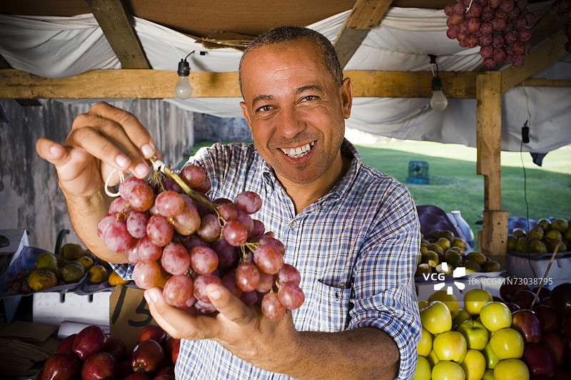 一位成熟男性手持一串红葡萄的肖像，圣多明各，多米尼加共和国图片素材