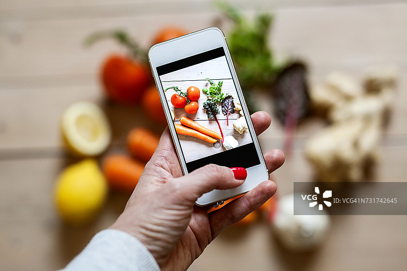 女人用智能手机拍摄蔬菜图片素材