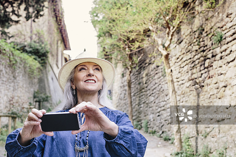 在意大利托斯卡纳菲耶索莱的鹅卵石街道上拍摄的时尚中年女性图片素材
