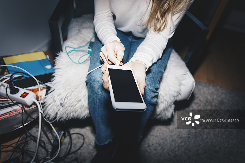 女子在大学宿舍为手机充电的身体中部照片图片素材