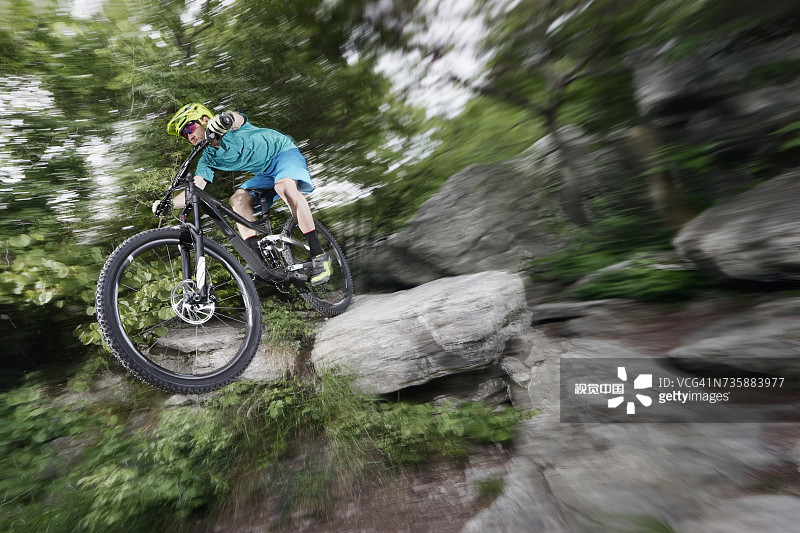 山地自行车骑手在岩石森林小路上飞驰图片素材
