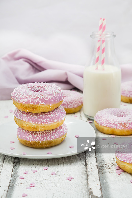 粉色糖霜和糖粒甜甜圈与一瓶牛奶图片素材