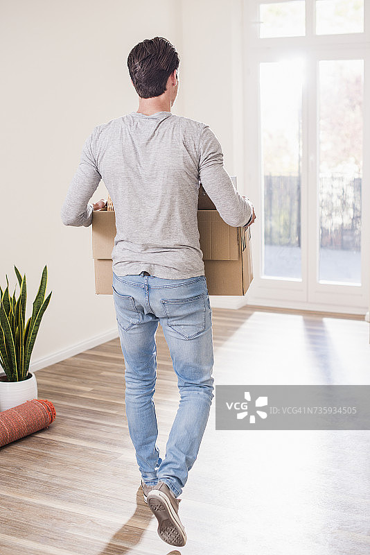 年轻男人在新家搬运纸板箱图片素材