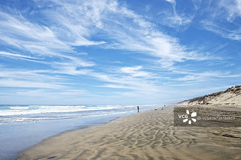 男人在新西兰北岛的九十英里海滩钓鱼图片素材