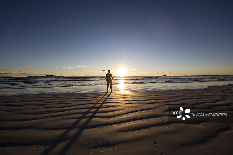 男子站在海滩上看着日落，澳大利亚西澳大利亚州图片素材