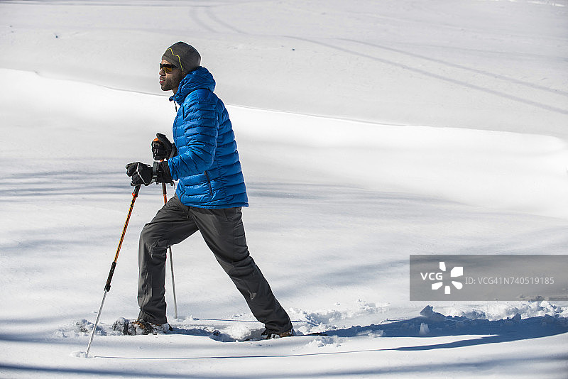 男子在阳光明媚的冬日雪地里行走图片素材