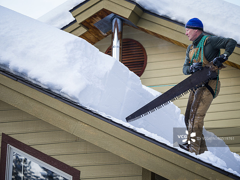 男人清理屋顶上的积雪，美国爱达荷州麦考尔图片素材
