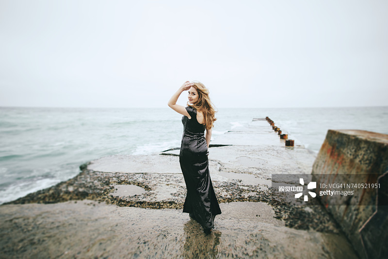 在海边，一位穿着连衣裙，面带微笑的白人妇女图片素材