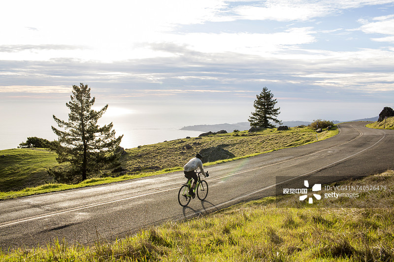 在海边道路上骑自行车的白人男子图片素材