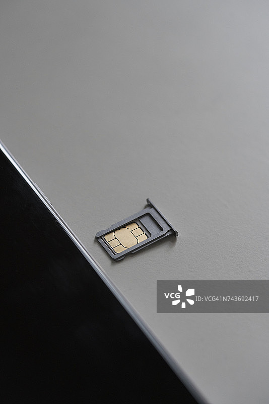 白色桌子上手机旁边的托盘中的SIM卡特写图片素材