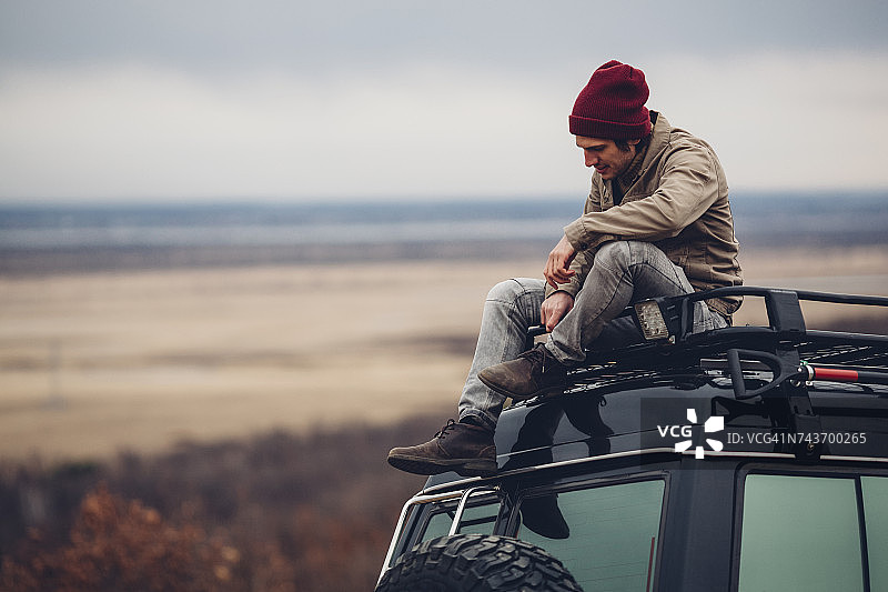 男子坐在俄罗斯阿穆尔州布拉戈维申斯克市的运动型多用途车顶上欣赏风景图片素材