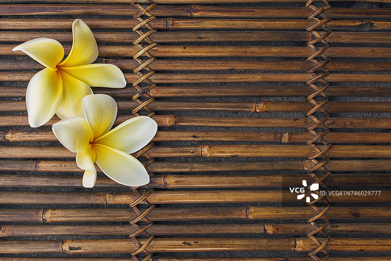 竹席上的黄色鸡蛋花图片素材