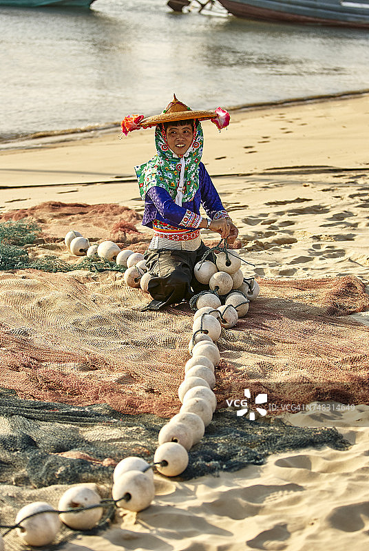 中国福建大作：穿着传统服装在海滩上修补渔网的女渔民图片素材