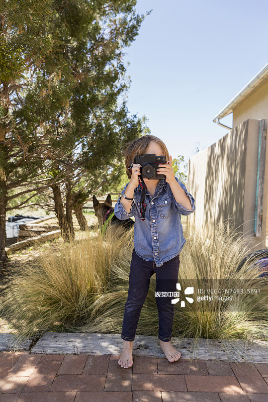 在房子附近用相机拍照的白人男孩图片素材