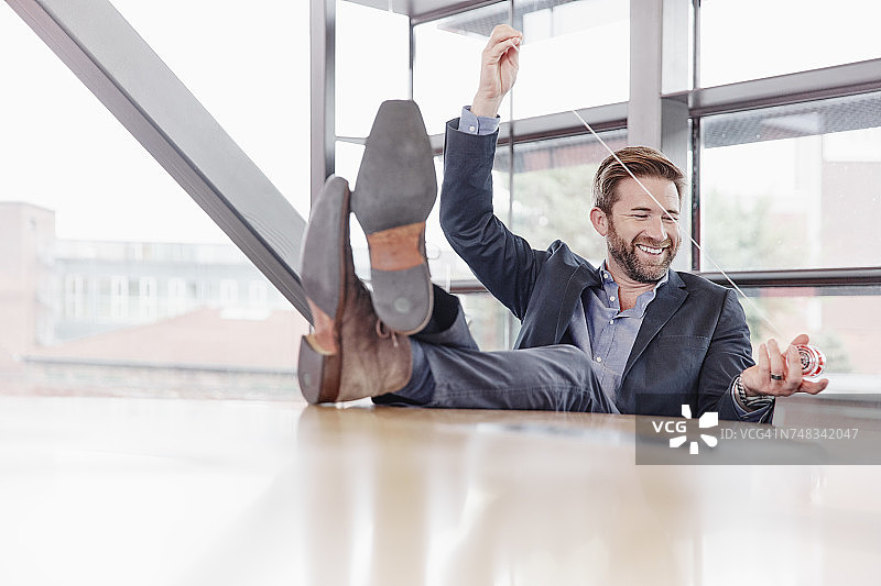 快乐的商人把脚放在桌子上玩溜溜球图片素材