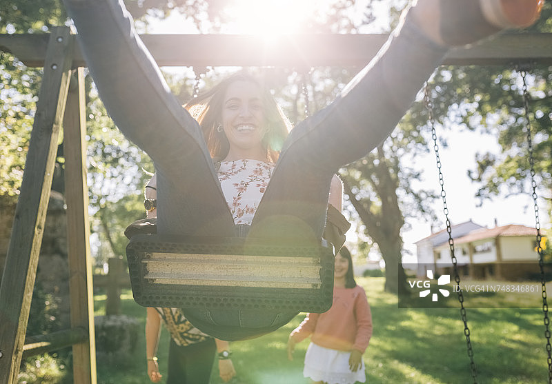 快乐的年轻女人在荡秋千图片素材