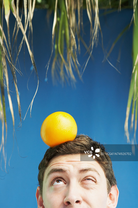 头顶橘子的年轻男人图片素材