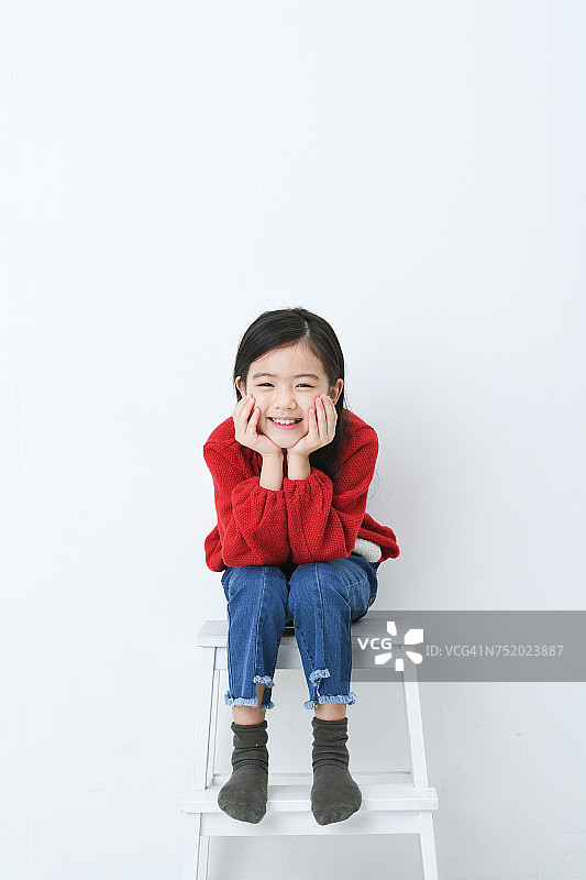 女孩坐在白色背景的椅子上图片素材