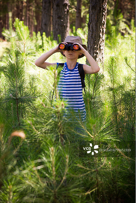 男孩在树林里使用双筒望远镜图片素材