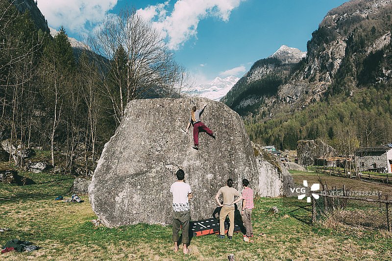 在意大利伦巴第观看年轻女子攀岩的成年攀岩爱好者背影图片素材