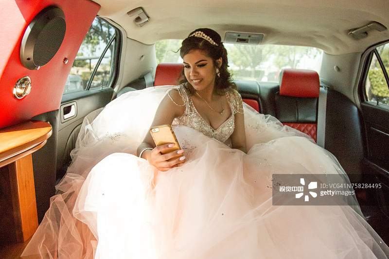 微笑的西班牙女孩在豪华轿车里用手机发短信图片素材