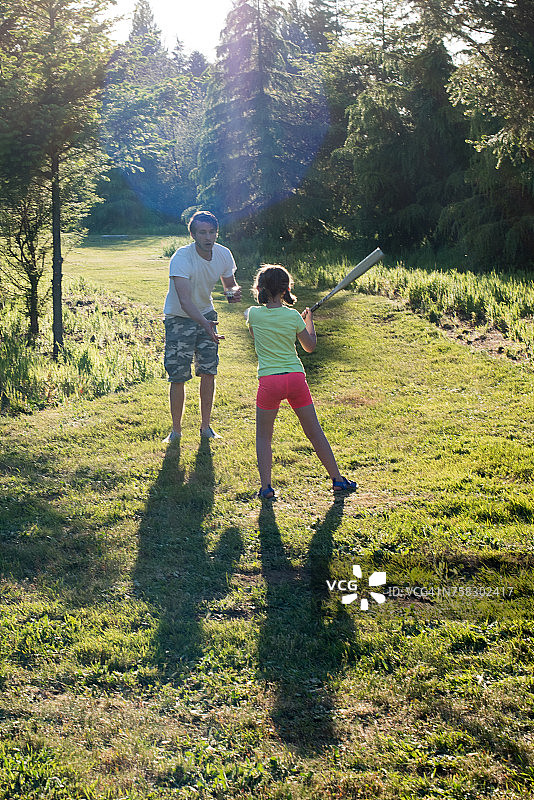 在户外练习棒球和球的击球技巧的男人和年轻女孩图片素材