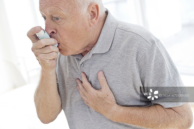 老年男人使用吸入器，捂着胸口图片素材