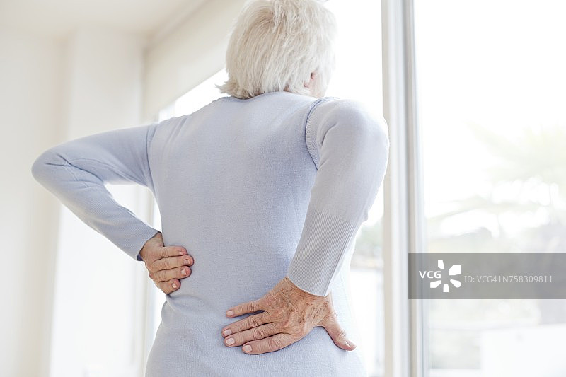 年长妇女揉痛的背部图片素材