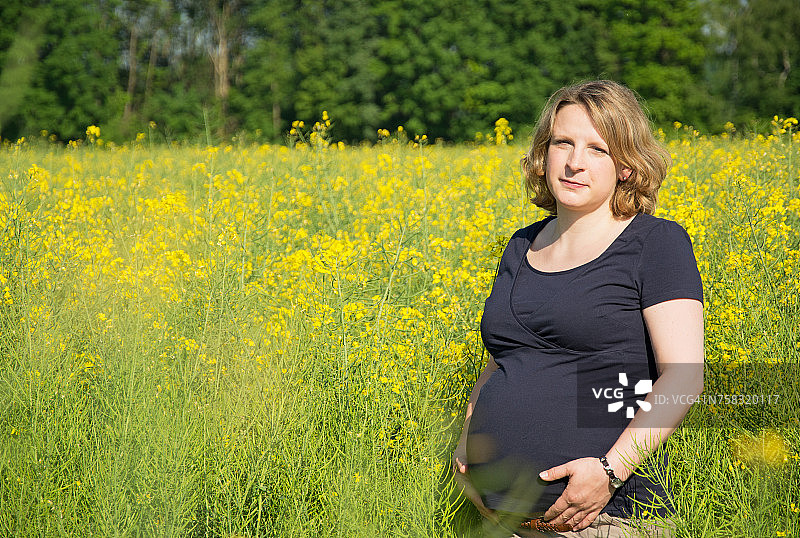 站在油菜花田里的孕妇图片素材