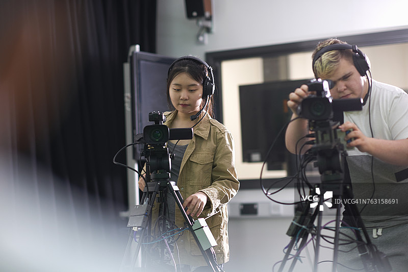 大学生在电视台演播室拍摄节目的肩上视角图片素材