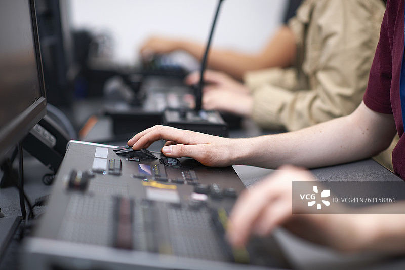 男女大学生在电视演播室的调音台旁图片素材