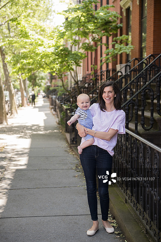 纽约布鲁克林，母亲抱着男婴（6-11个月）走在城市街道上图片素材