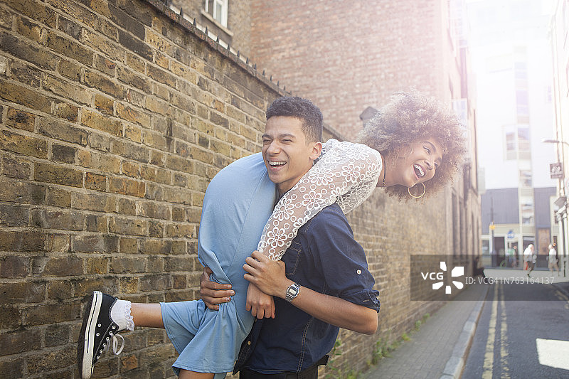 在街上嬉戏的年轻夫妇，男人背着女人图片素材