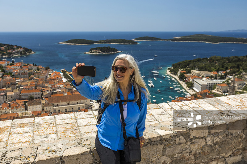 白人妇女在风景优美的海景前用手机自拍图片素材