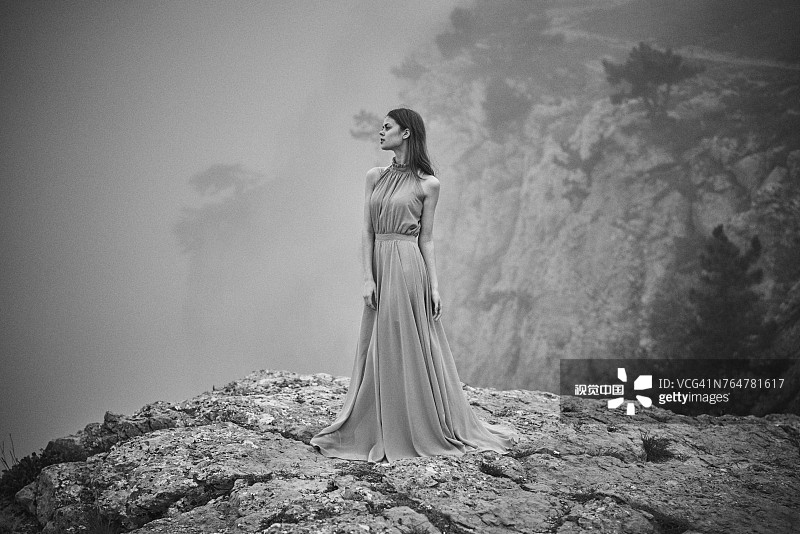 在雾中穿着衣服的女人站在岩石上图片素材